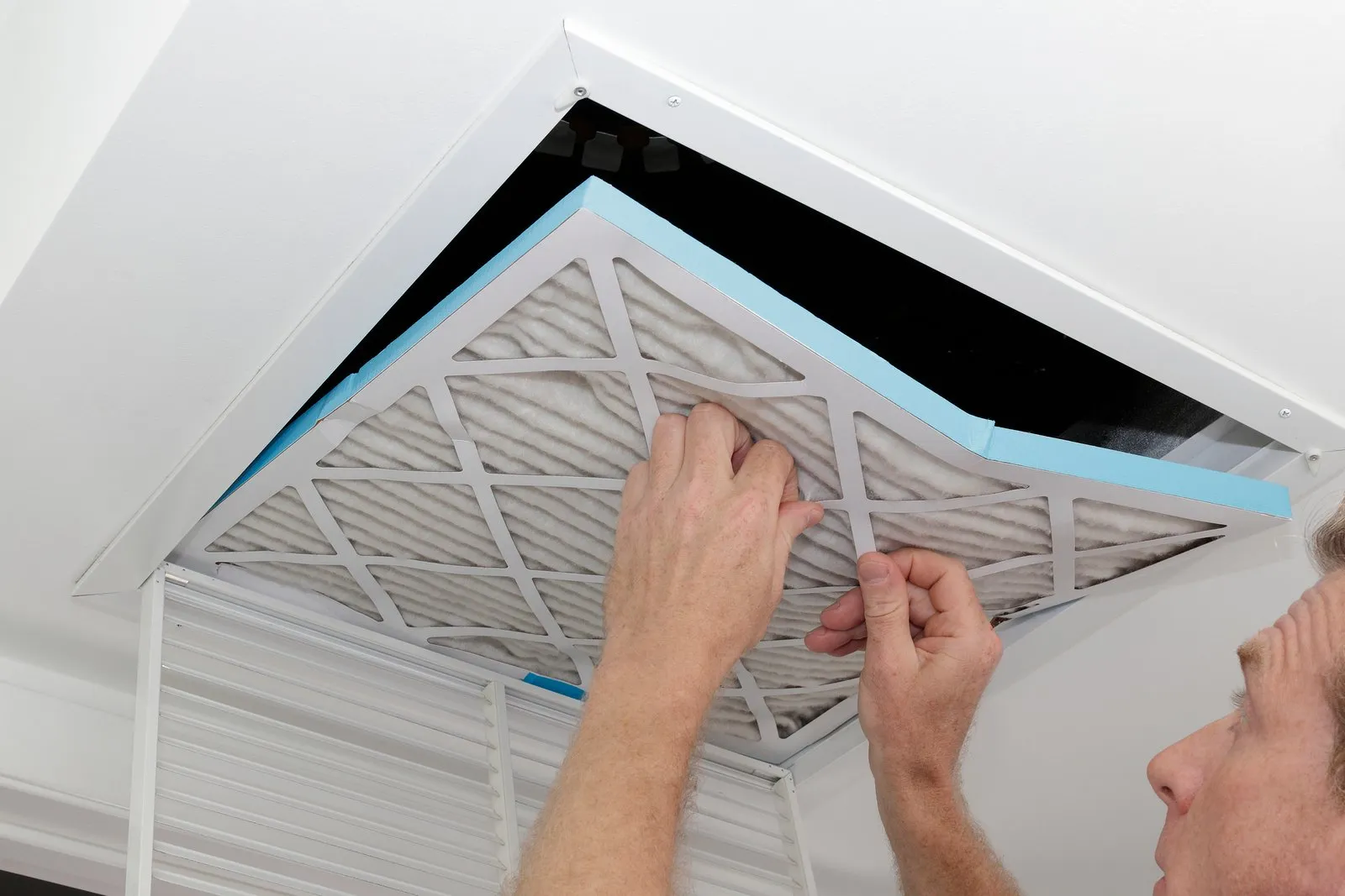Technician cleaning an air duct vent in a Lone Tree home